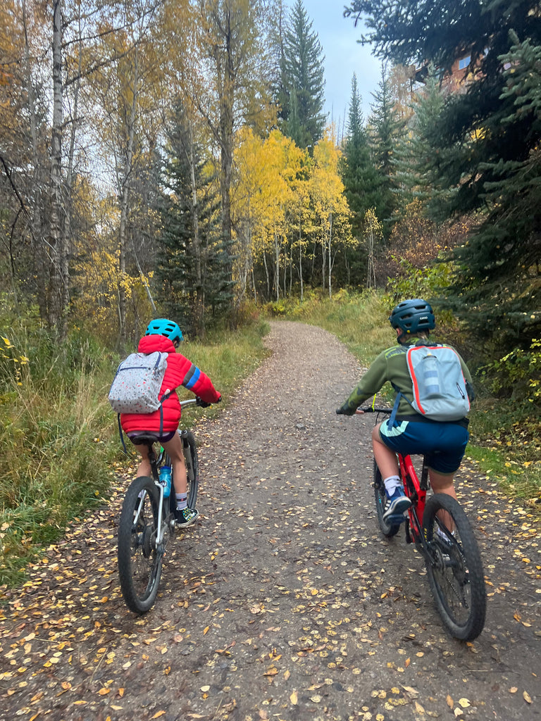 Kids ride bikes to school in the fall leaves of Steamboat