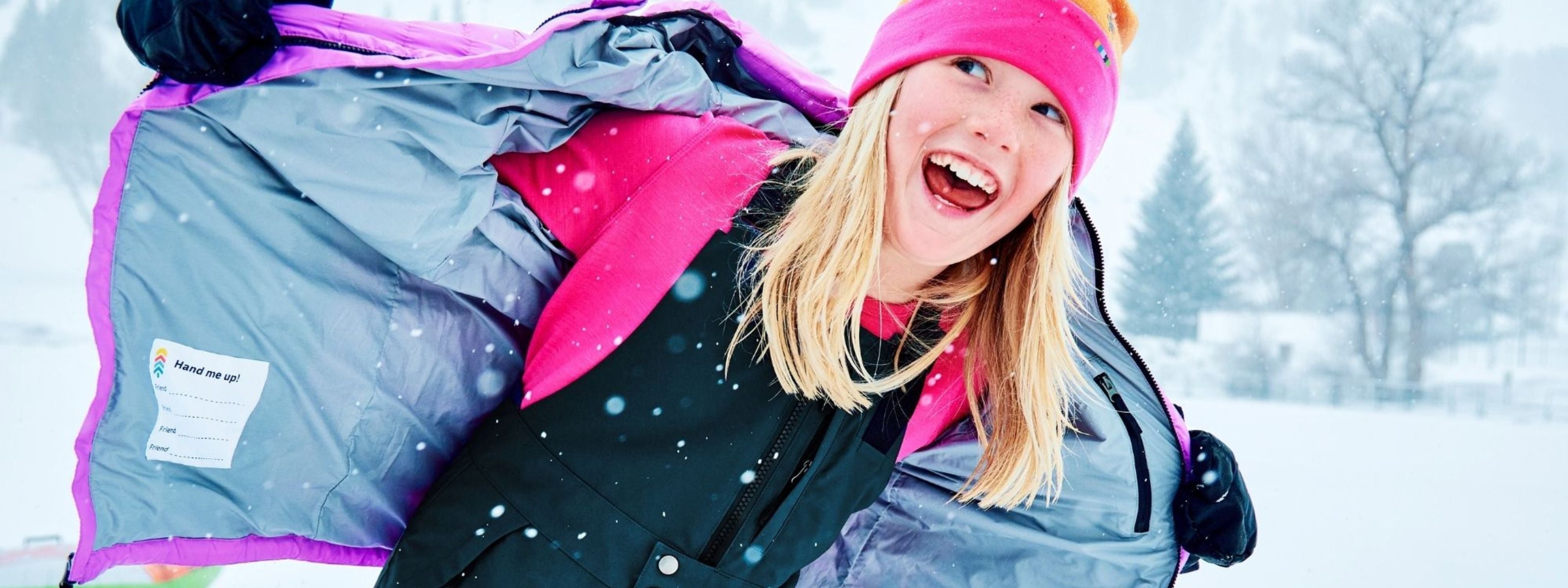 Girl with Town Hall puffy on and open to the front, wearing new colorful bib pants with snow falling