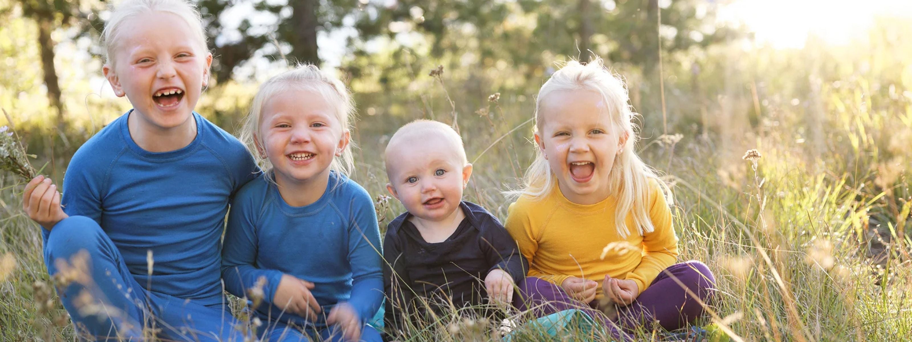 four kids in merino wool baselayers smiling
