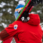 Person wearing a red jacket repaired with a snowy gray NOSO Gear Repair Patch, showing how these waterproof patches seamlessly extend the life of outdoor apparel.