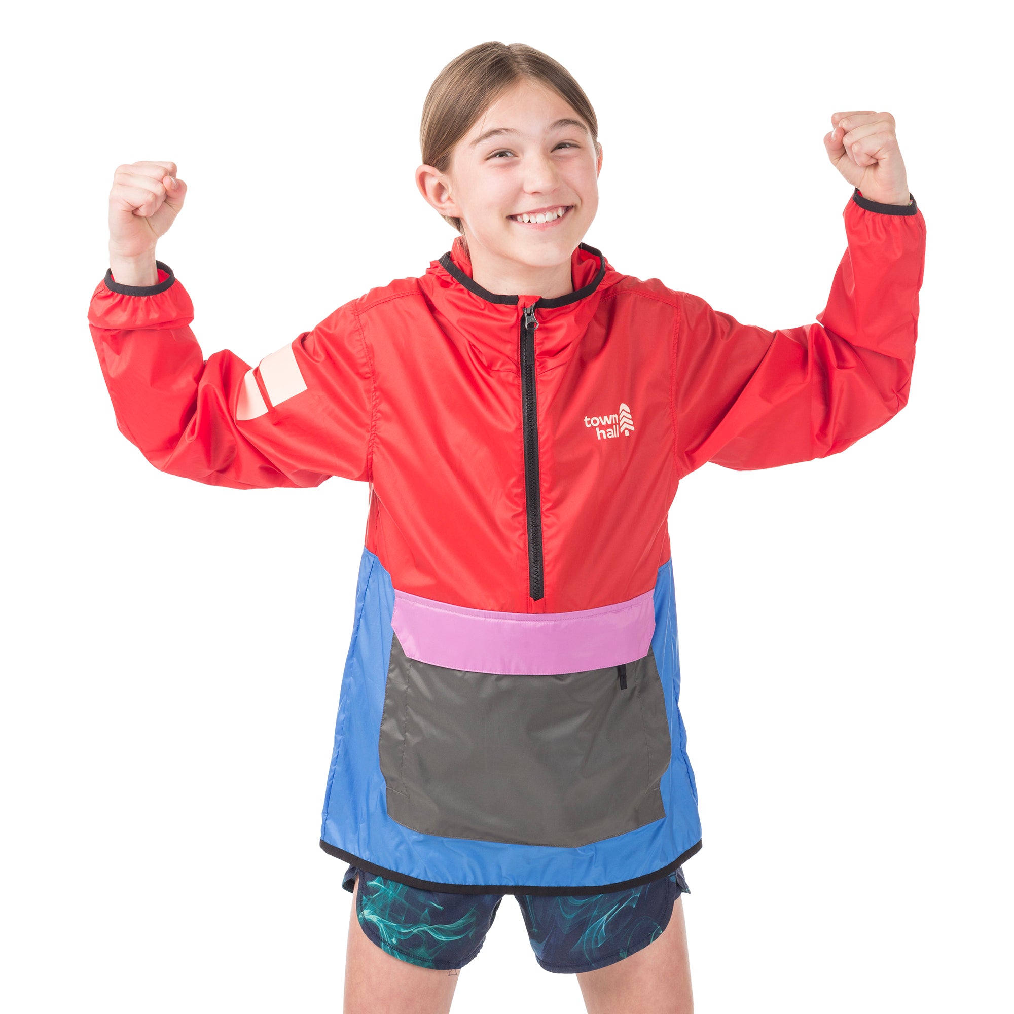 Girl exploring outdoors in the bright Goji Berry About Town Anorak, showcasing the Town Hall logo, protective hood, and weather-resistant design for year-round adventures.