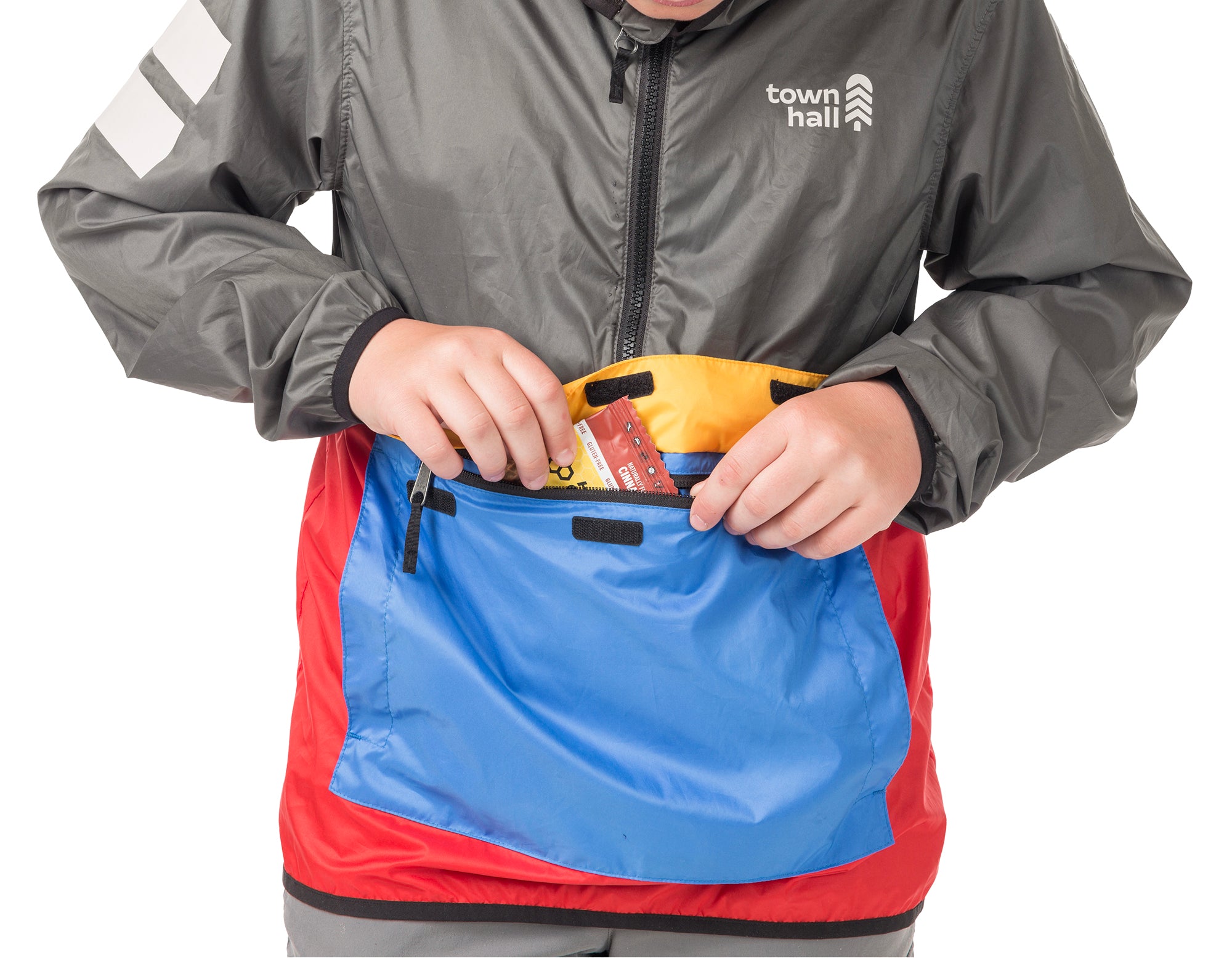 Boy demonstrating the About Town Anorak's built-in stuff sack pouch feature, perfect for packing away when weather clears during hiking or biking adventures.