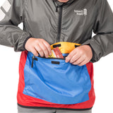 Boy demonstrating the About Town Anorak's built-in stuff sack pouch feature, perfect for packing away when weather clears during hiking or biking adventures.