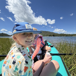 Two children in a kayak on a lake with a scenic background