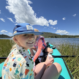 Two children in a kayak on a lake with a scenic background