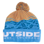 A multicolor knit pom-pom beanie hat featuring a striped orange and yellow top section, a blue mountain pattern, and a light blue cuff with white text reading 'LOVE OUTSIDE Steamboat Springs, COLORADO'.