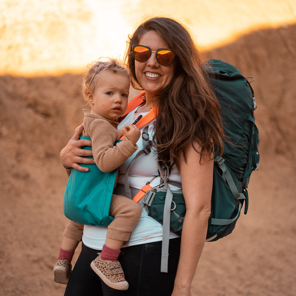 Mom and child hiking in a canyon with a TrailMagik kid carrier on. Loving outside and smiling.