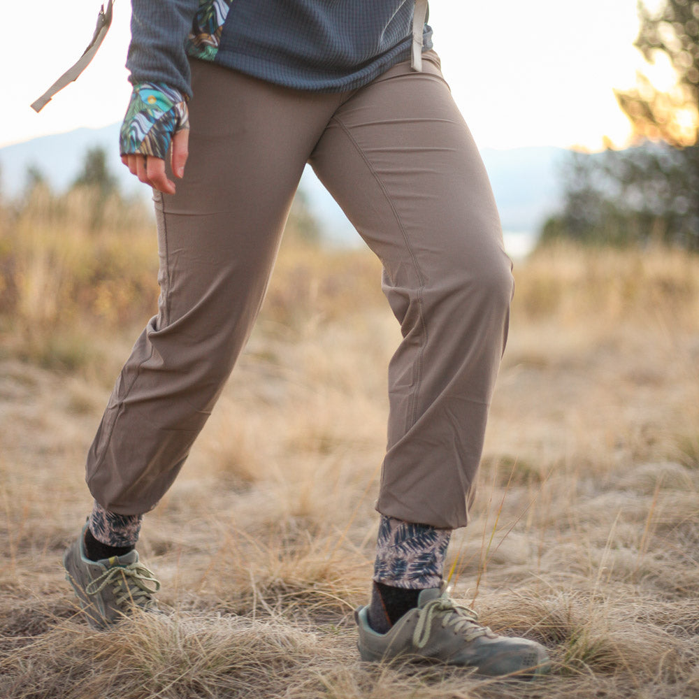 Youer Women's Follow-Through Pants. Woman walking in woods at sunset in outdoor pants.