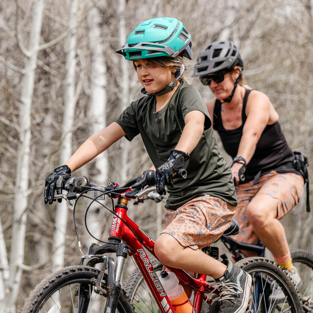 Mom and daughter riding mountain bikes in Wild Rye shorts and wearing helmets