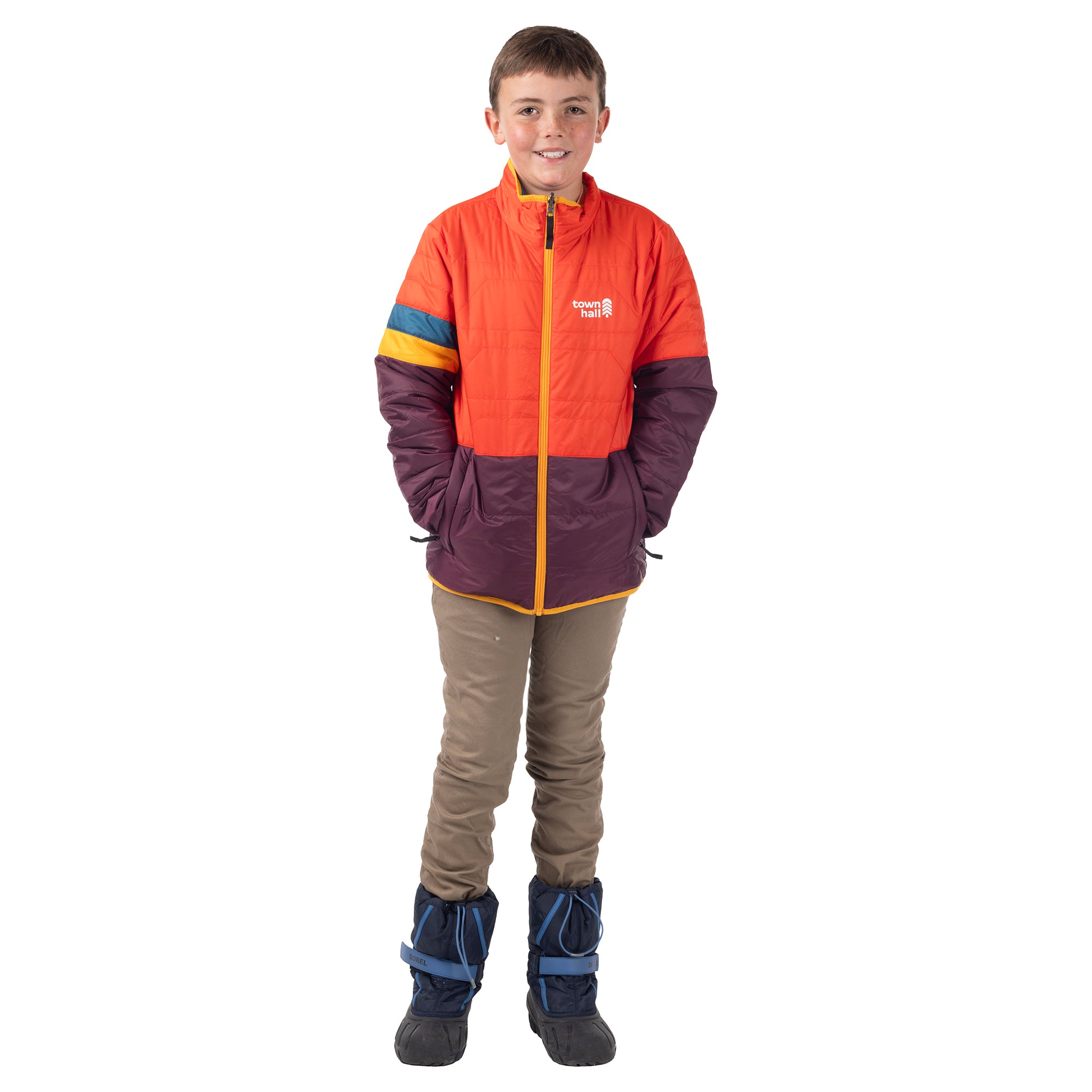 Child modeling the orange and plum Skip Town Insulated Jacket with hands in its pockets.