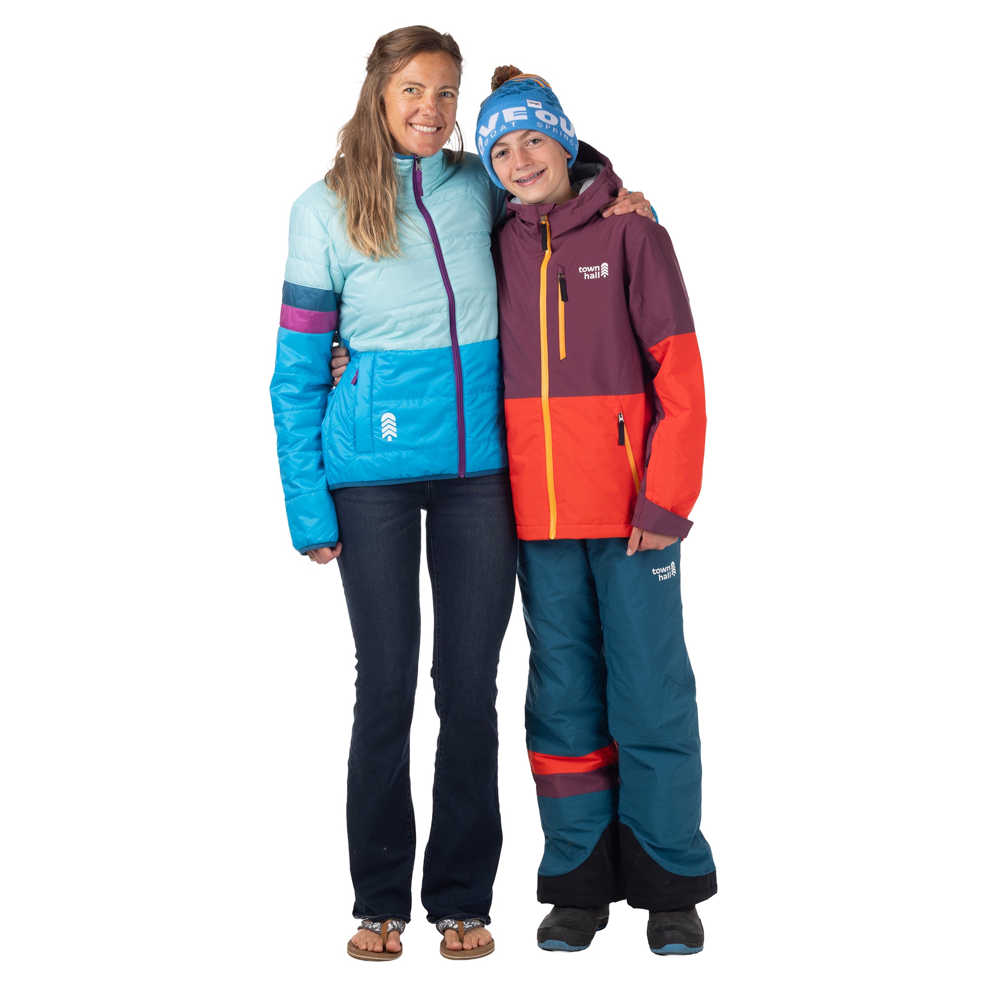Woman wearing an aqua and blue OuttaTown Reversible Jacket beside a child in Town Hall snow gear.