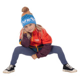 Child crouching in the blue Kids Love Outside Beanie with striped crown and pom-pom, wearing a colorblock puffy jacket.