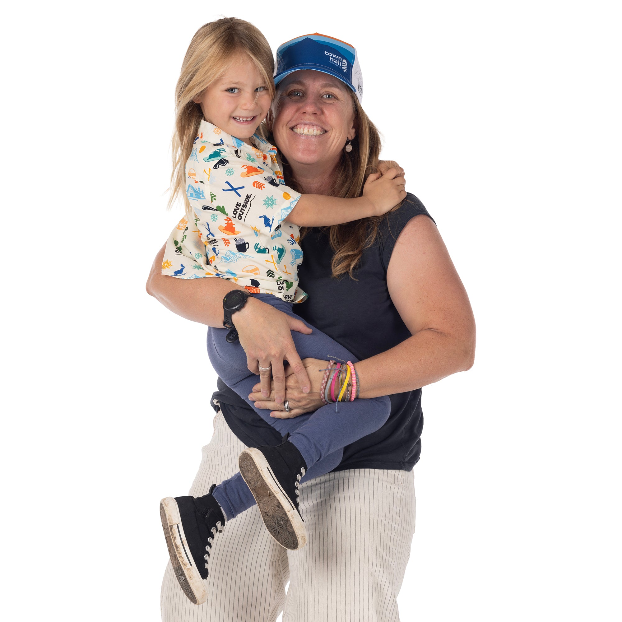 Adult holding a smiling child wearing Town Hall Kids Cabana Shirt in Vanilla with colorful ski-town print.