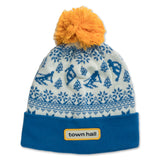 Blue kids beanie with playful snowy mountain scene and skier pattern, featuring the Town Hall logo on the folded cuff and topped with a cozy pom.