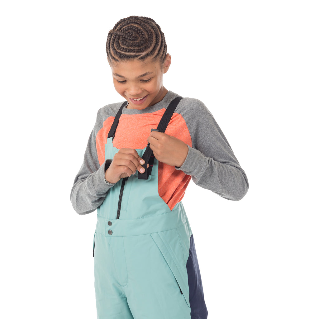 Child tilted to side showing the easy-adjust shoulder straps on Town Hall's Canton Winter Bib - a kid-friendly feature that helps extend the life of these sustainable snow pants. 