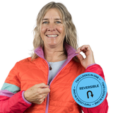 Woman wearing a colorful reversible jacket with a visible brand logo on a white background