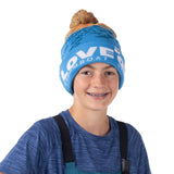 boy wearing blue beanie with Love Outside embroidered on cuff and colorful pom, smiling ready to play outside