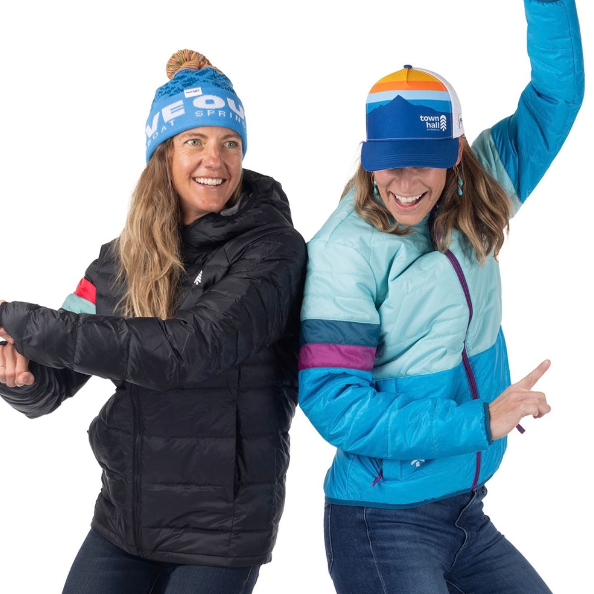 Two moms dancing, wearing bright colors and a Town Hall beanie with multiple colors and Love Outside embroidered on it.