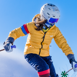 Person skiing with a helmet and goggles on a clear blue sky background
