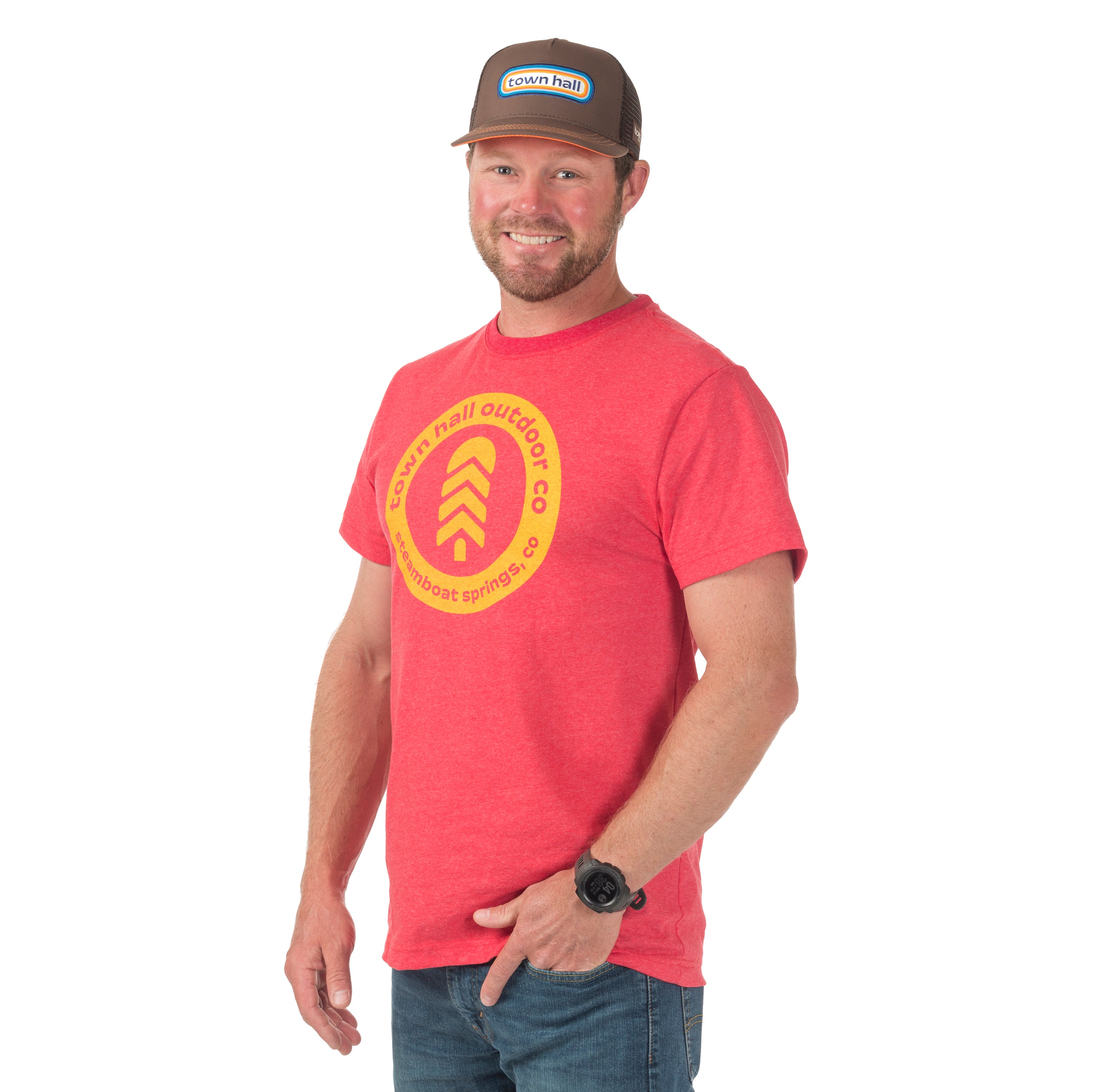 Man wearing sustainable Town Hall Adult Steamboat Badge Tee in Ruby color, featuring locally screen-printed mountain town design celebrating Colorado roots.